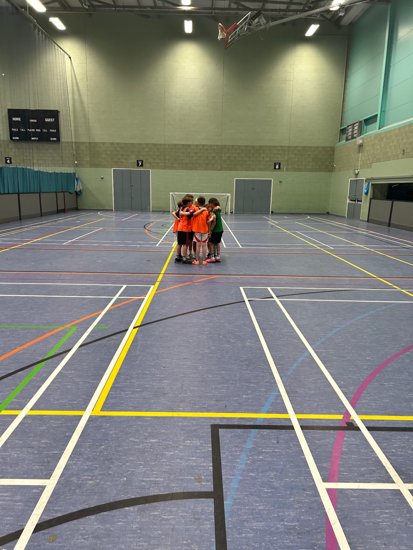 Young children in a team huddle on court