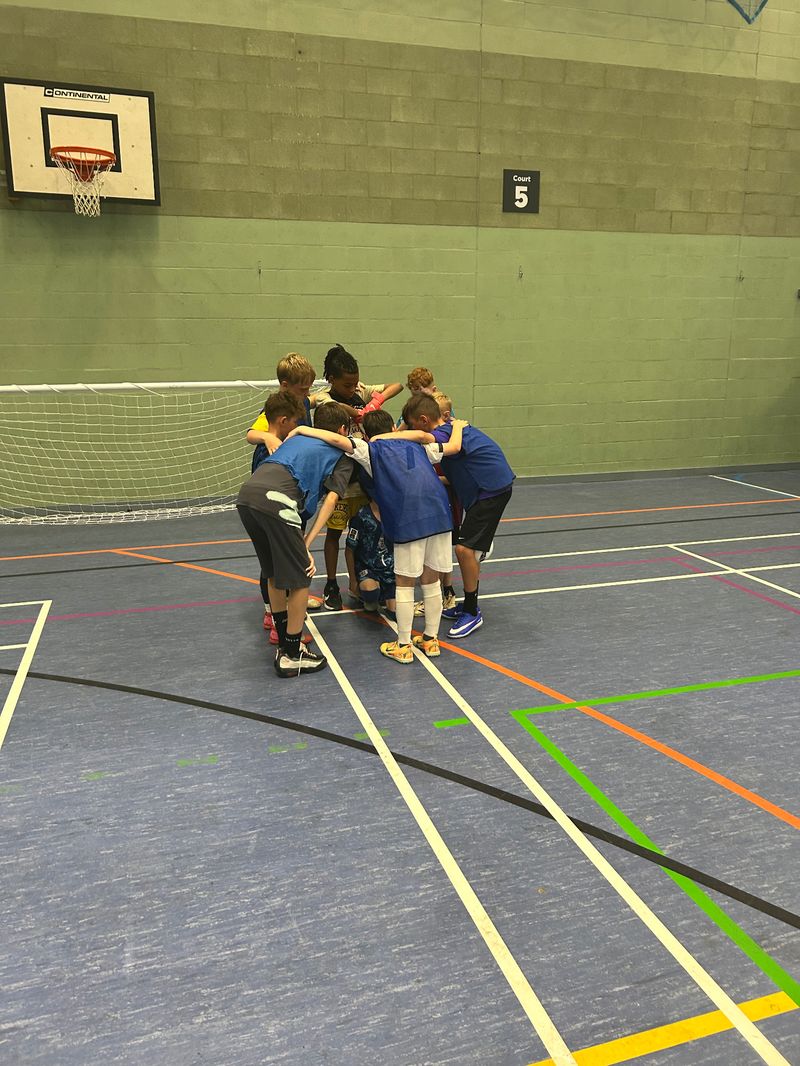 Children gathered in an enthusiastic team huddle during a sports birthday party