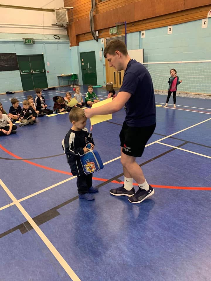 Coach presenting a certificate to a young child during a sports party